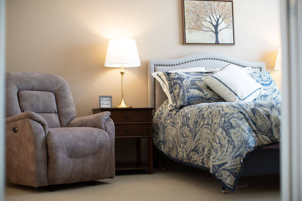 A furnished suite with a bed and a reading chair